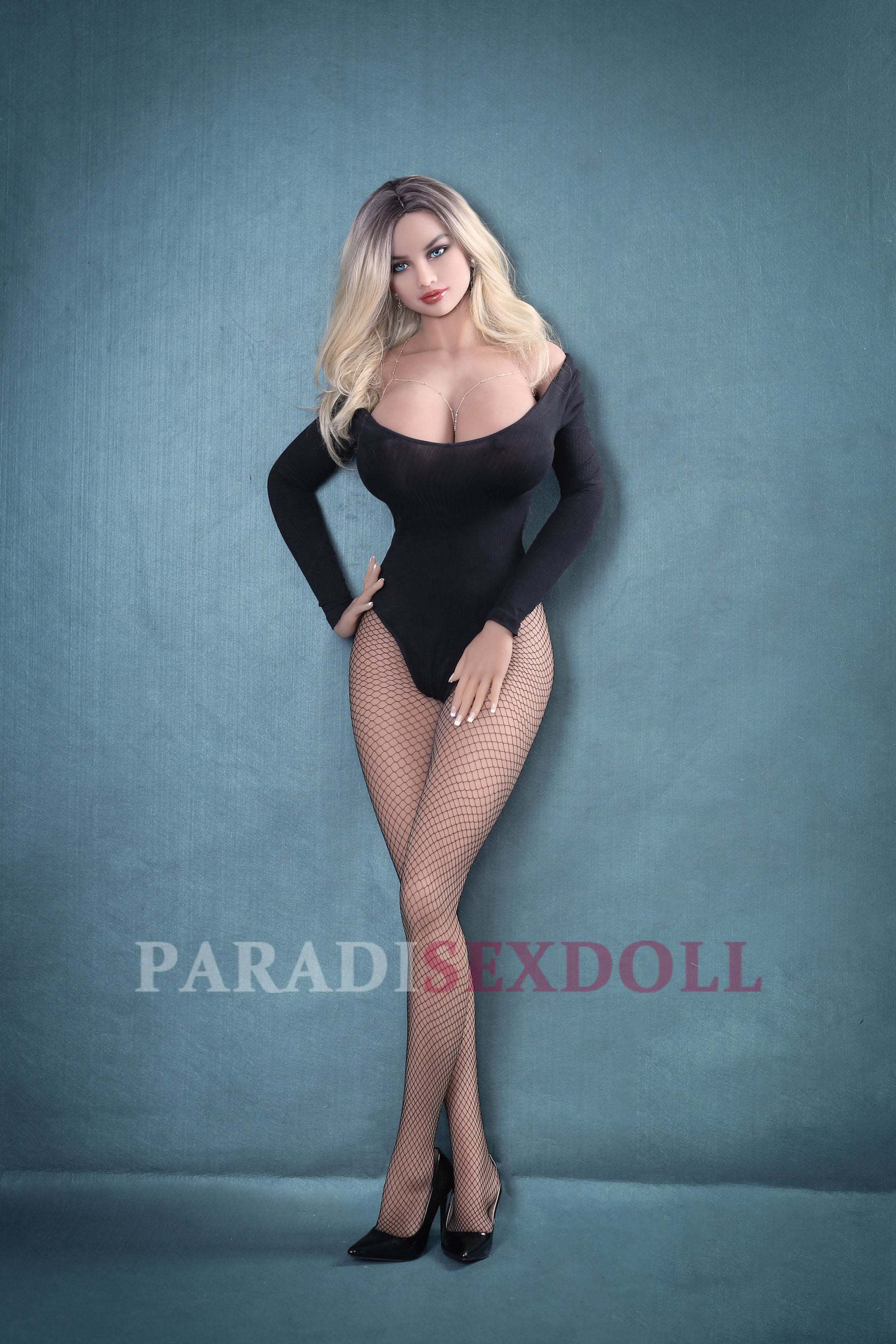 Full-body TPE sex doll Aaliyah elegantly posed in a black off-shoulder bodysuit and fishnet stockings, highlighting her long blonde hair and realistic curves against a teal background.