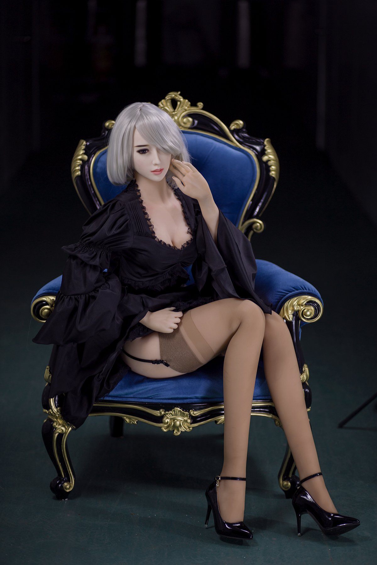 170cm Akiko sex doll in a black lace robe and sheer stockings, elegantly seated on a royal blue armchair, showcasing her platinum blonde hair and posing gracefully.