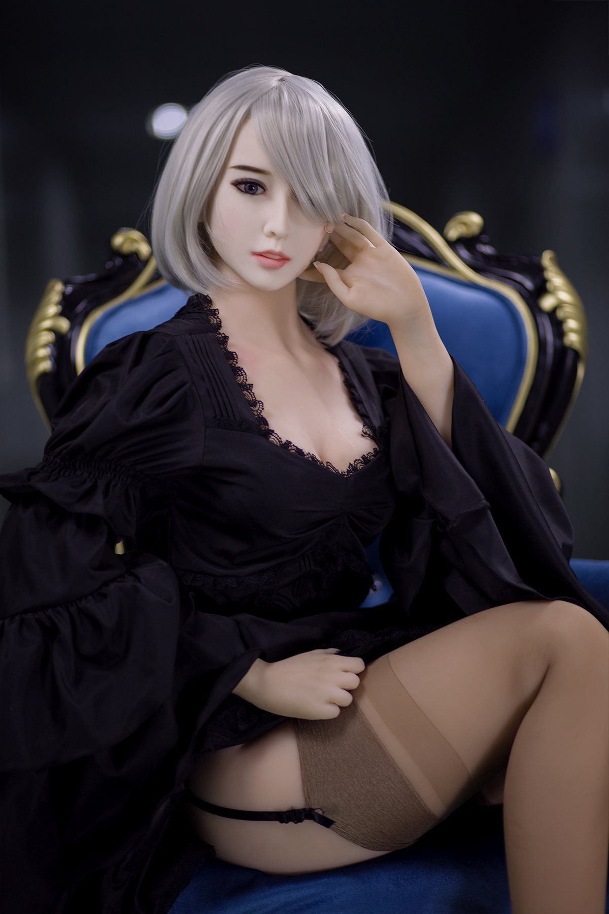 170cm Akiko realistic sex doll in an elegant black lace robe with wide sleeves and beige stockings, gracefully seated on a royal blue armchair, showcasing her sophisticated pose and stylish short platinum blonde hair.