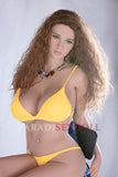 Lifelike K-Cup sex doll with long wavy brown hair, vibrant green eyes, and a bright yellow bikini, elegantly posed on a chair, complemented by a colorful necklace.