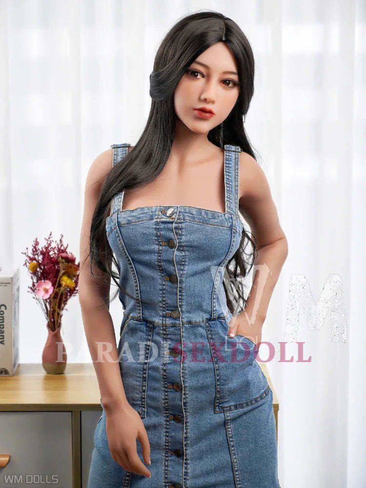 Lifelike Asian TPE sex doll with a soft, realistic expression, wearing a fitted denim dress, standing confidently in front of a bright window, showcasing long, flowing black hair and detailed facial features.