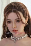 Detailed image of the Asian silicone sex doll Qiuyue, showcasing realistic facial features, long brown hair styled elegantly, and a sparkling necklace. The doll's expression highlights lifelike qualities, perfect for collectors and enthusiasts.