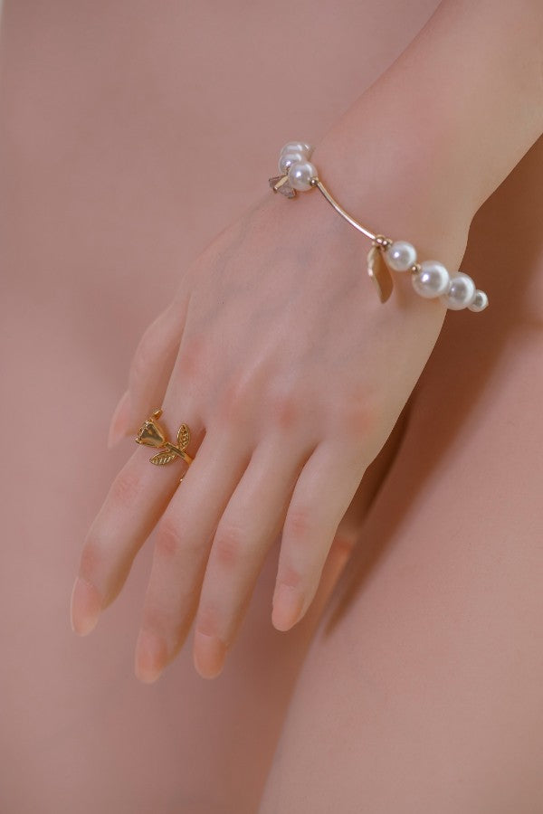 Close-up of the realistic hand of the Asian silicone sex doll Qiuyue, showcasing intricate details of the fingers and a delicate gold ring with a leaf design. The hand is adorned with a pearl bracelet, emphasizing the lifelike quality of the doll.