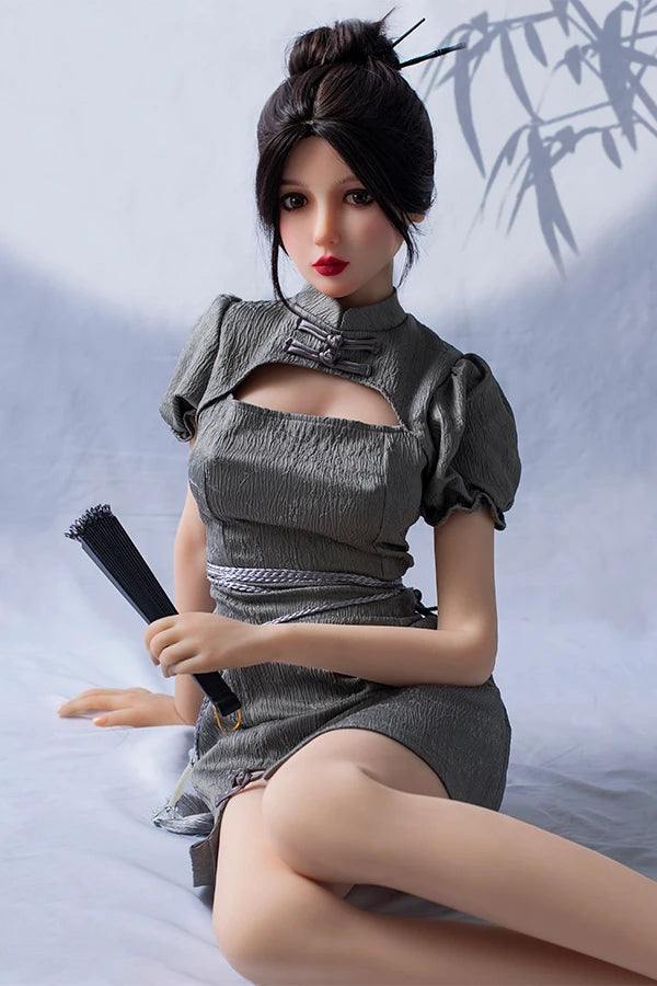 Lifesize Chinese sex doll Winni in a stylish gray dress with puff sleeves, elegantly seated and holding a traditional black fan, against a subtle bamboo-patterned backdrop.