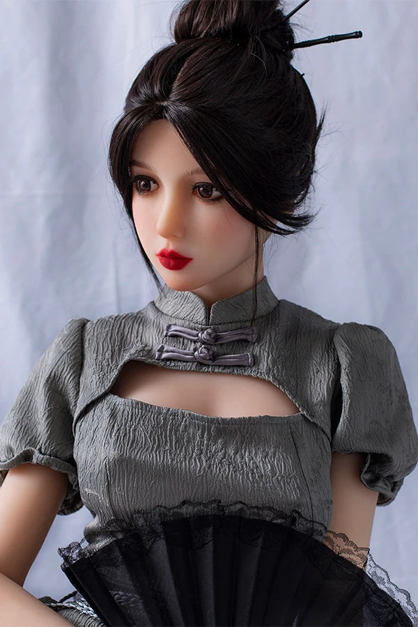 Lifesize Chinese sex doll Winni elegantly dressed in a gray puff-sleeve dress with a stylish collar, holding a delicate black lace fan, exuding a sophisticated charm, against a soft neutral backdrop.