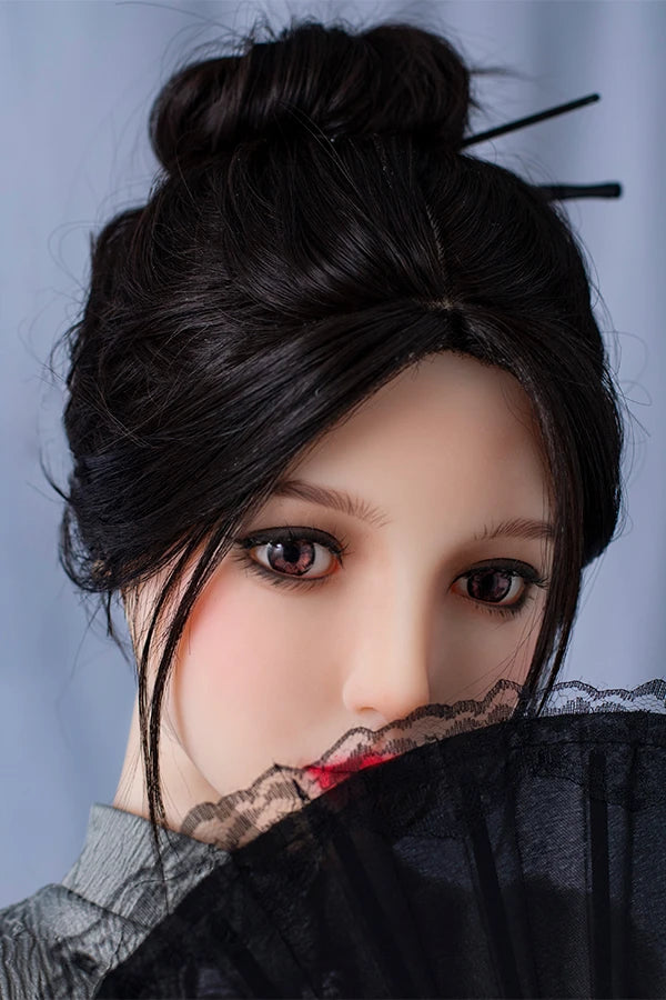 Close-up of lifesize Chinese sex doll Winni with detailed facial features and an elegant updo hairstyle, gracefully holding a delicate black lace fan. Dressed in a stylish gray puff-sleeve dress, the backdrop is soft and neutral, highlighting her sophisticated look.